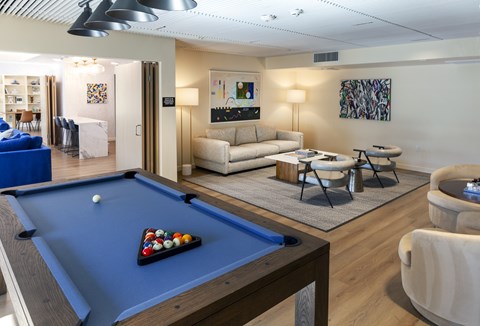 A pool table with a blue cloth and a white ball in the foreground.