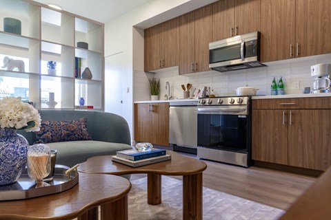 A modern kitchen with a wooden table and a sofa in the living room.