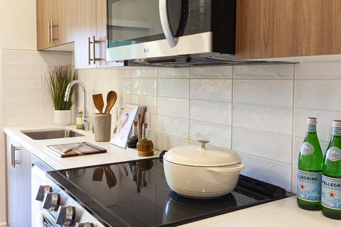 A kitchen with a black stove top and a white pot on it.