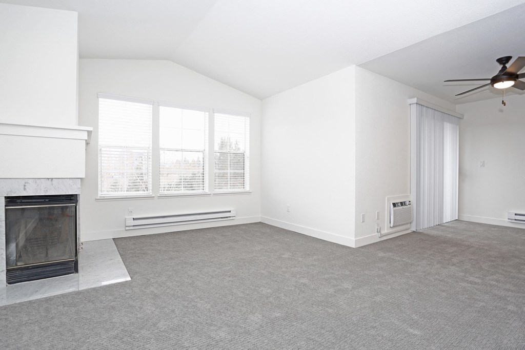 an empty living room with a fireplace and a ceiling fan