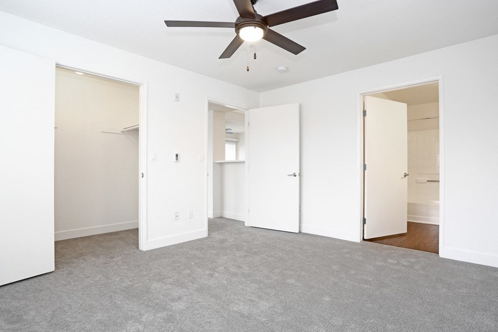 a bedroom with white walls and a ceiling fan