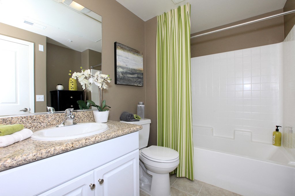 a bathroom with a green shower curtain and a sink and a toilet