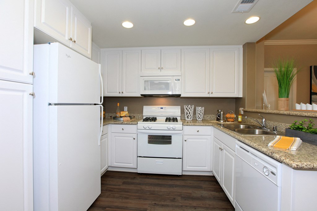 a kitchen with white cabinets and appliances and a counter top