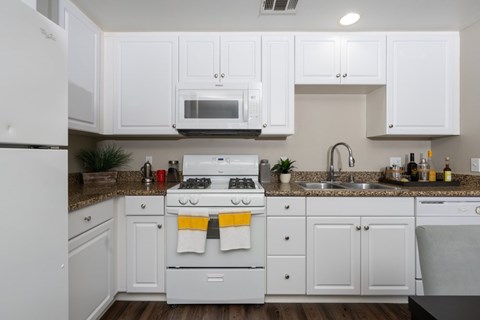 A white kitchen with a stove top oven and a microwave above it.