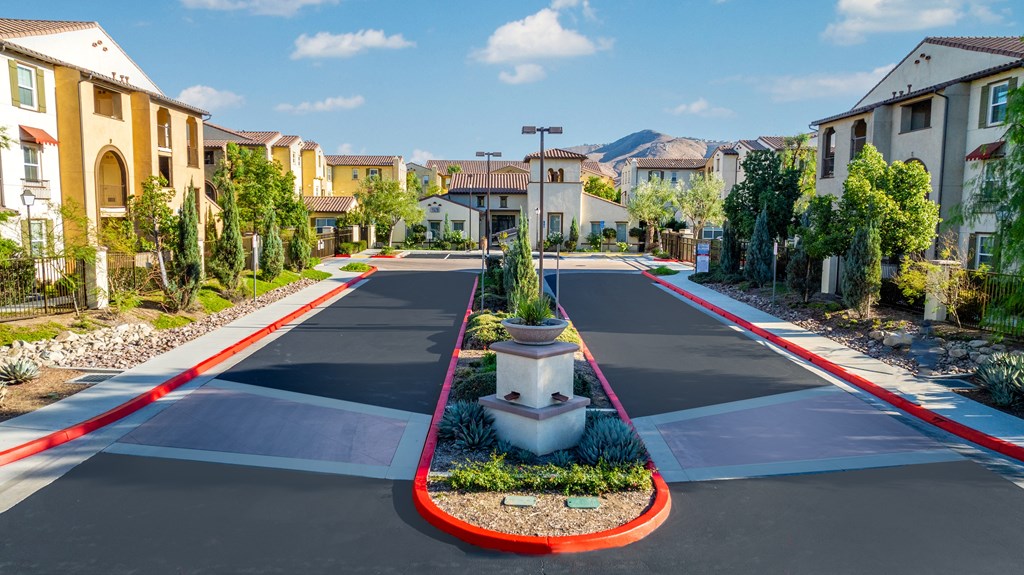 an empty street in a neighborhood with houses and plants on a cross walk