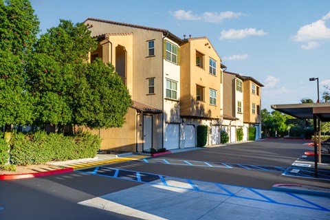 an empty parking lot in front of a row of apartment buildings
