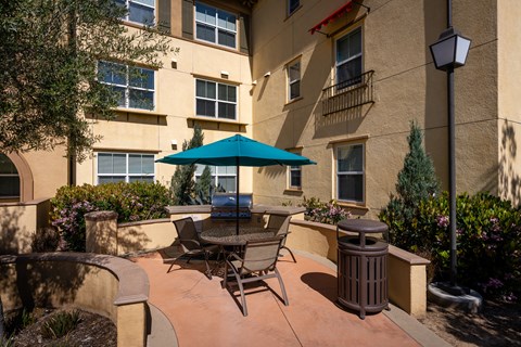 a patio with a table umbrella and chairs in front of Paseos at Magnolia
