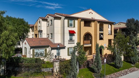 a group of apartment buildings with trees and a sidewalk