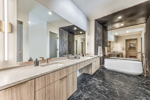 A modern bathroom with a marble floor and wooden cabinets.