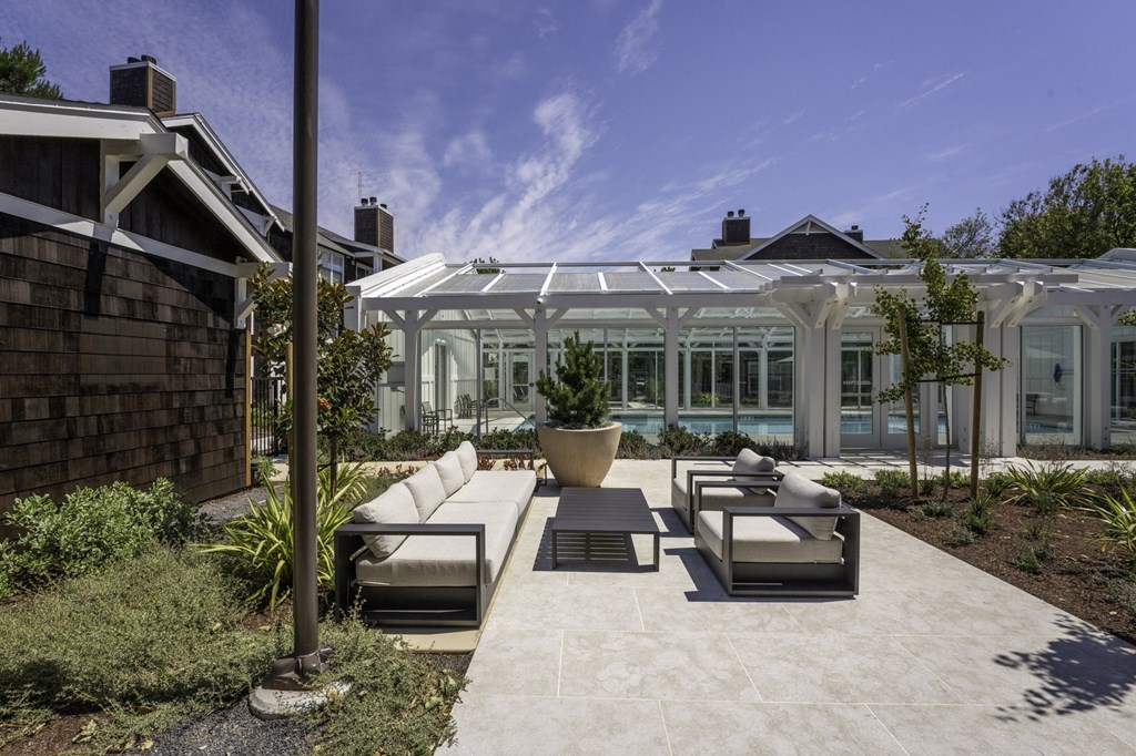 a patio with furniture in front of a glass greenhouse