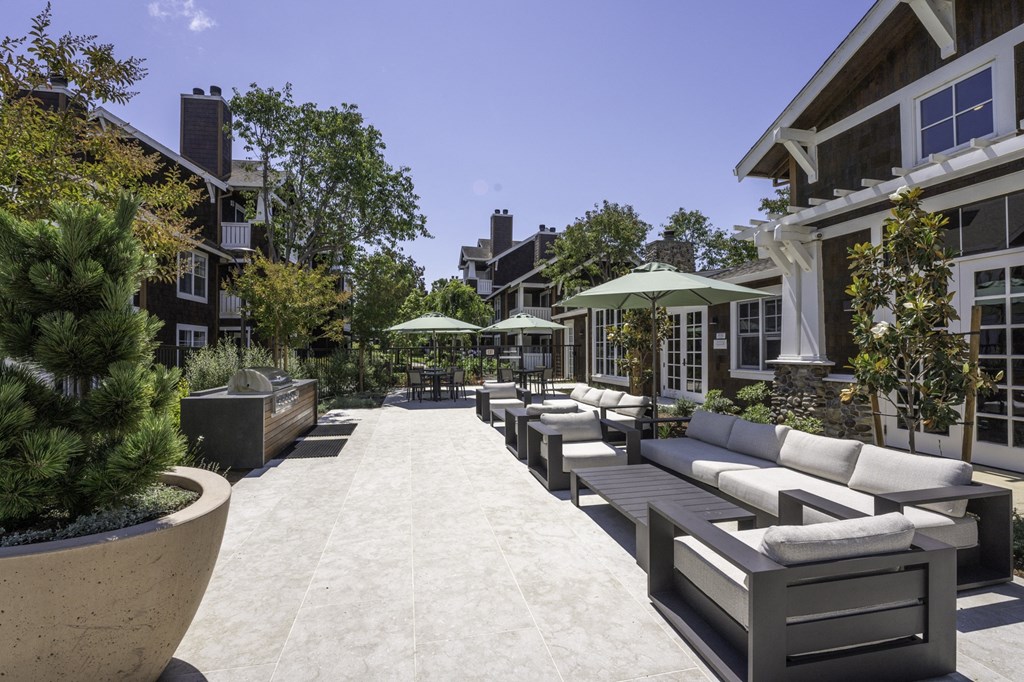 a lounge area with couches and umbrellas in a courtyard