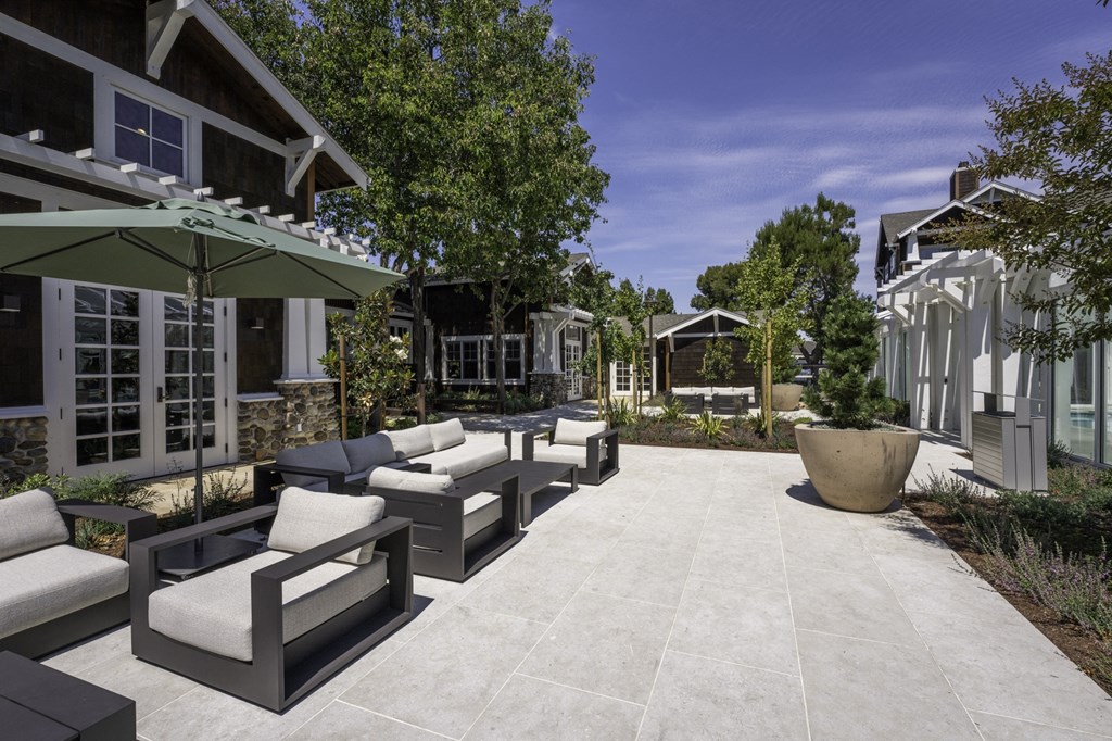 a patio with furniture and umbrellas in front of a house