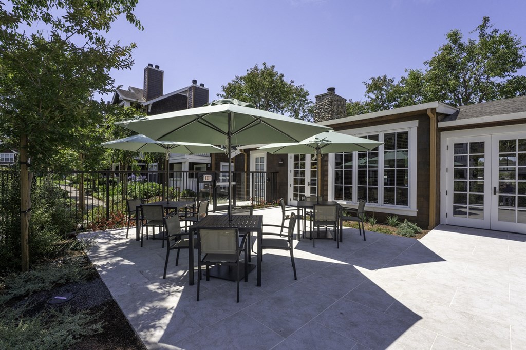 a patio with tables and umbrellas in front of a building
