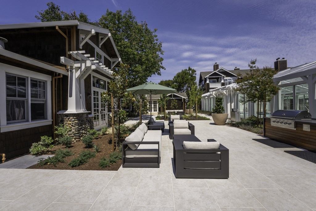 a patio area with benches and umbrellas in front of houses