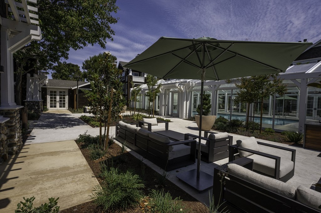 a patio with couches and umbrellas in a courtyard
