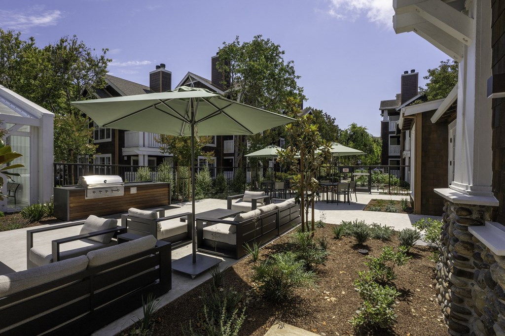 a patio with couches and umbrellas in front of a house
