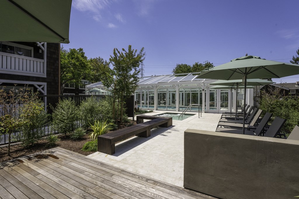 a courtyard with benches and tables and a glass greenhouse