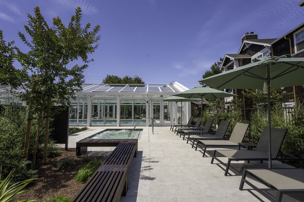 a courtyard with benches and umbrellas and a glass greenhouse