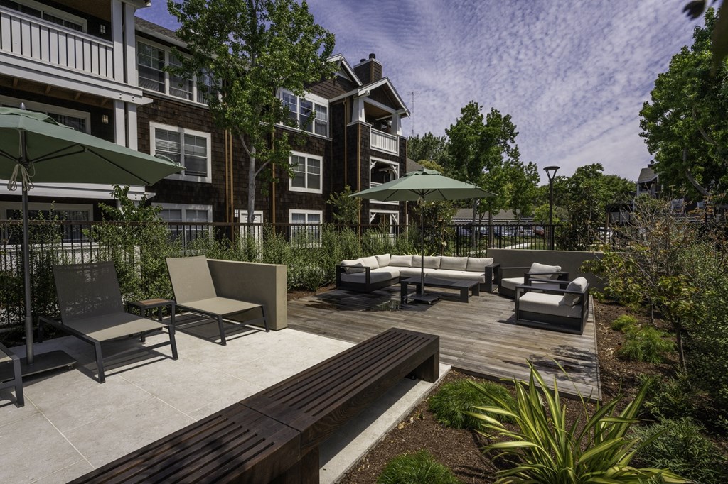 a patio with furniture and umbrellas in front of a building