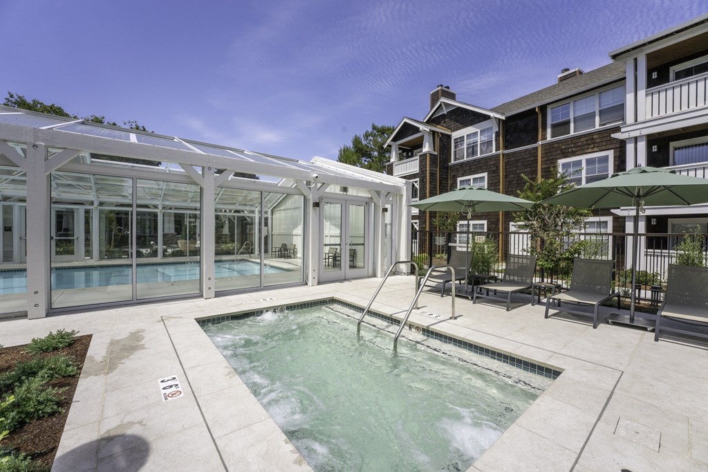a pool with chairs and umbrellas next to a building