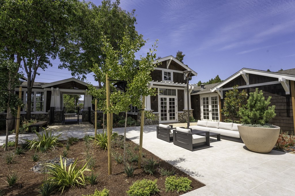 a patio with a couch and chairs in front of a house