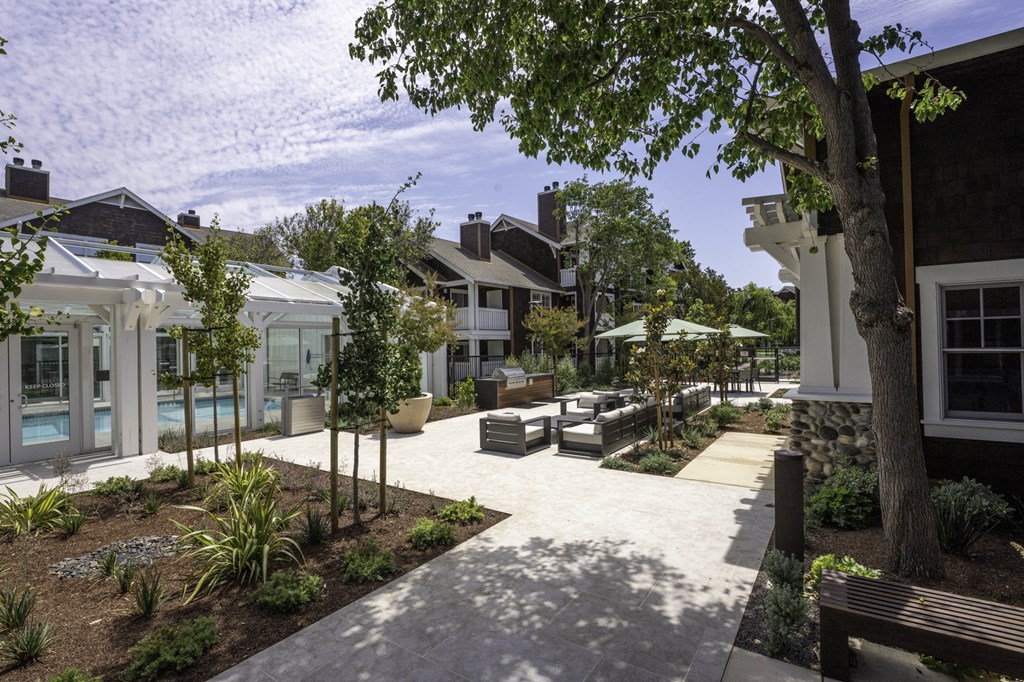 a courtyard with benches and trees in front of houses