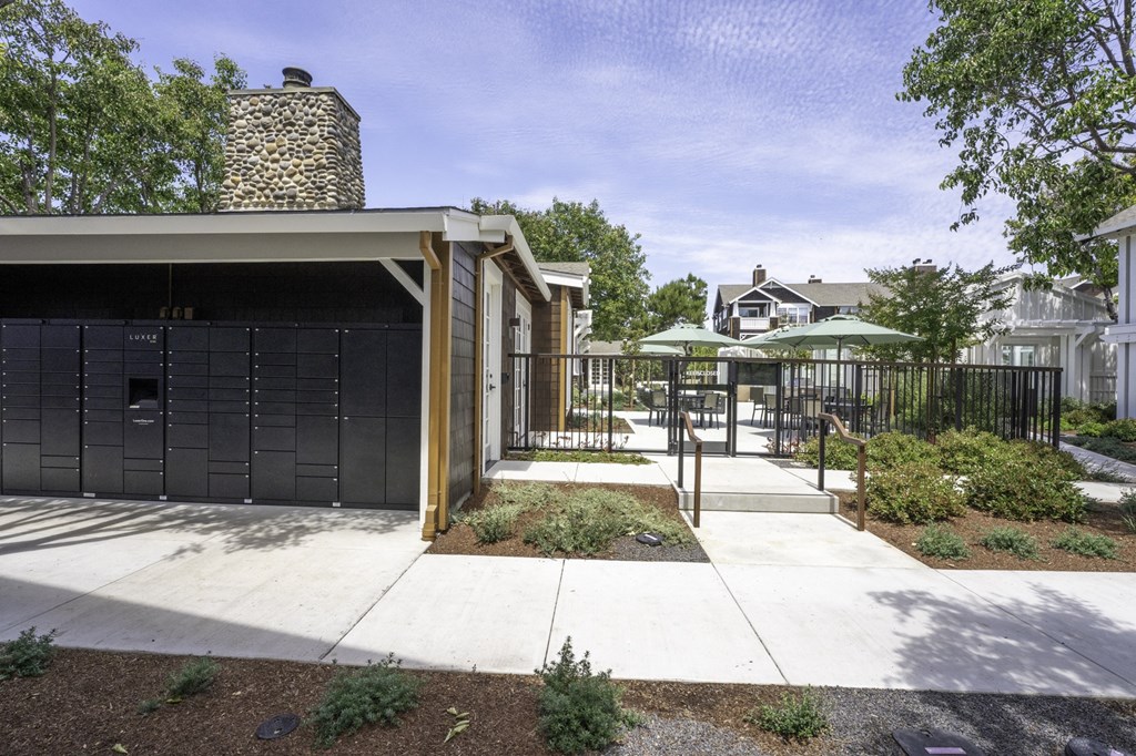 the yard of a home with a black fence and a patio with umbrellas
