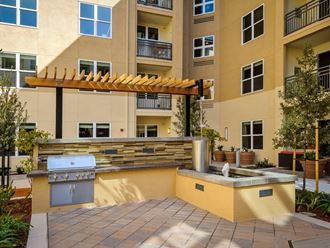 a patio with a grill and a fountain in front of an apartment building