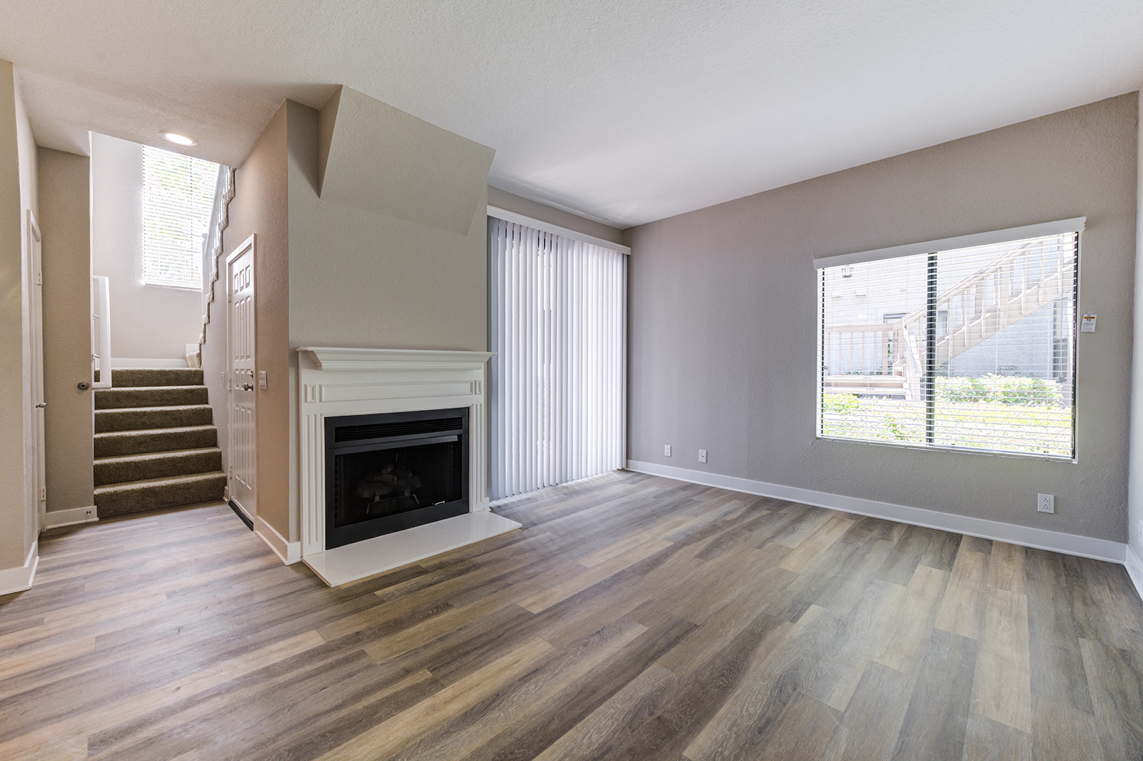 Living area with sliding glass doors to balcony, windows, and fireplace adjacent to stairs