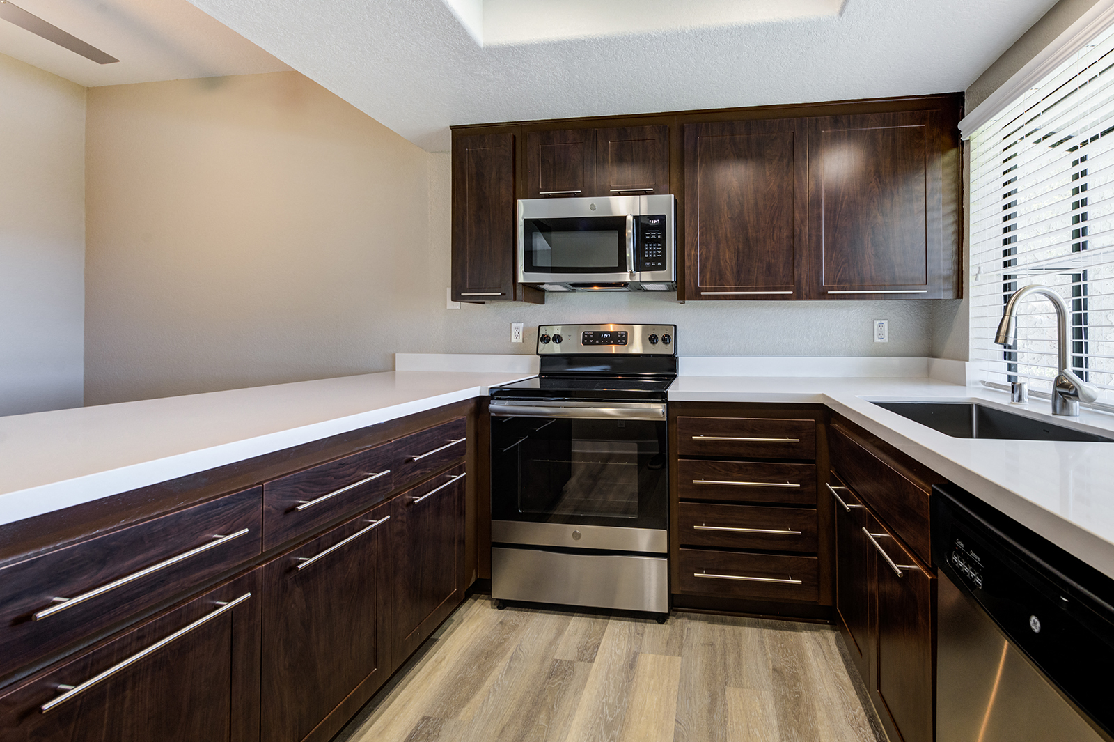Apartments for Rent Laguna Niguel CA - Pointe Niguel - Kitchen with Wood-Style Floor, Brown Cabinets, White Quartz Countertops, and Stainless Steel Appliances