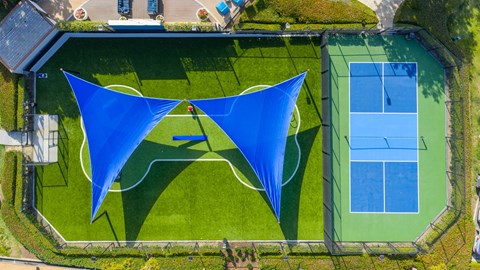 A tennis court with a blue shade structure.