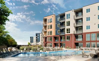 an apartment complex with a swimming pool and lounge chairs