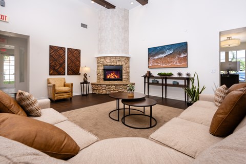 A living room with a fireplace and a painting of a beach scene on the wall.