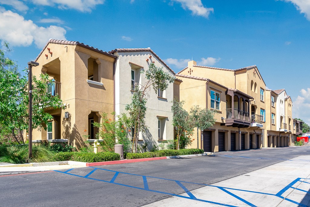 a row of apartment buildings with blue parking mats in front of them