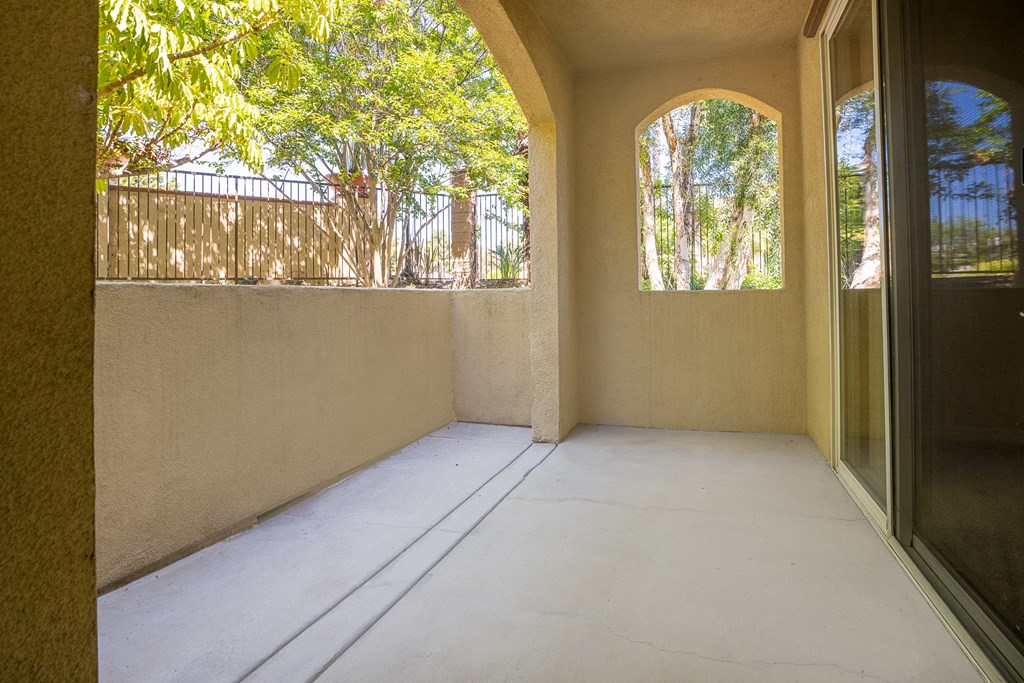 a patio with a sliding glass door and trees in the background