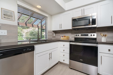 a kitchen with white cabinets and stainless steel appliances and a window