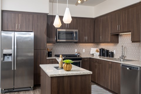 A kitchen with a refrigerator, microwave, and a counter with a pumpkin on it.
