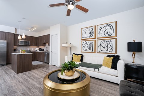 A modern living room with a white couch, a coffee table, and a painting on the wall.