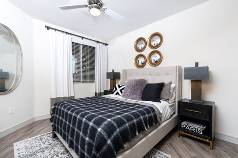 A bedroom with a bed, a mirror, a dresser, and a ceiling fan.