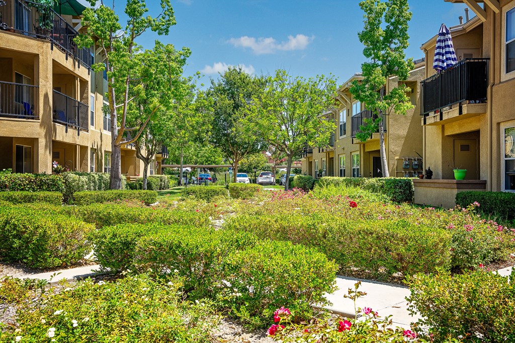 a courtyward with flowers and trees in the middle of an apartment complex