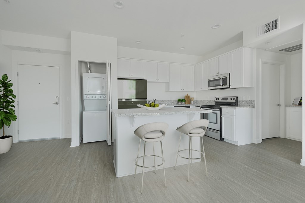 A white kitchen with a bar and stools.at 422 South Lake, California, 90057