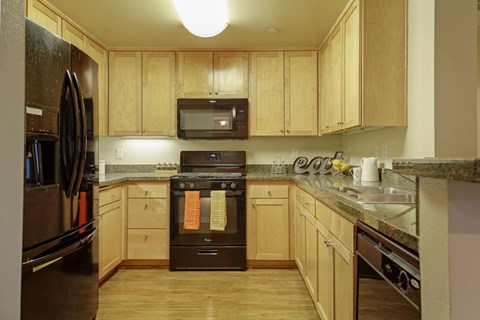A kitchen with wooden cabinets and a black oven.
