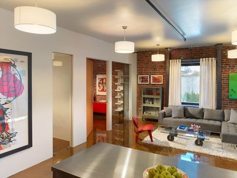 A modern living room with a grey couch and a red chair.