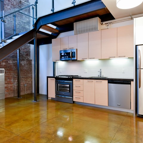 A kitchen with a stainless steel refrigerator and a black countertop.