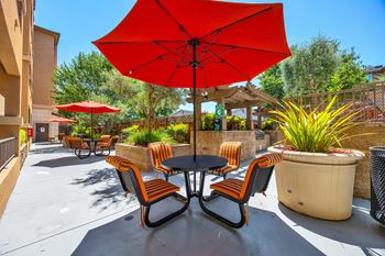 a patio with a table and chairs under a red umbrella