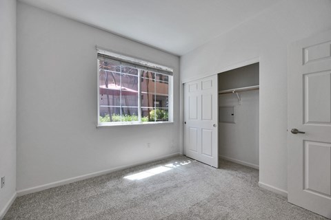an empty bedroom with a window and a closet