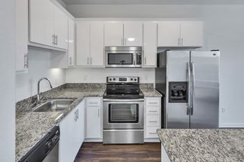 a kitchen with white cabinets and granite counter tops and stainless steel appliances