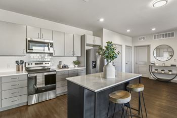an open kitchen with stainless steel appliances and a marble counter top at Parkside at Littleton Village, Littleton, CO