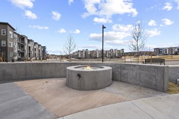 a fire pit in a park with buildings in the background at Parkside at Littleton Village, Littleton, CO