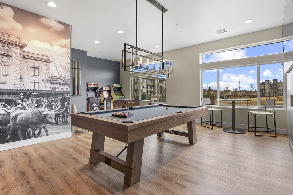a pool table in a clubhouse with a view of a bar and a large window at Parkside at Littleton Village, Littleton, Colorado